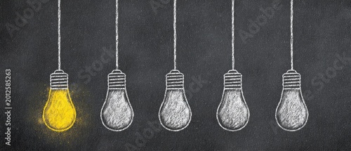 A single glowing yellow lightbulb stands out among several unlit, chalk-drawn bulbs
