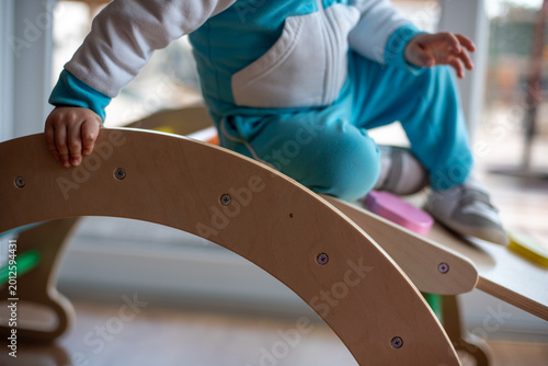 Slika na platnu Toddler playing on wooden pikler rocker arch developing motor skills