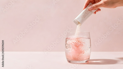 Beauty collagen powder pouring into glass of water, minimalist high-end commercial for skincare supplement with massive copy space on pink background.
