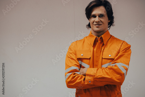 Fotografía Industry Professional Portrait: A focused industrial professional, exuding competence and experience in his vibrant orange workwear, stands confidently arm crossed