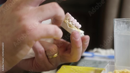 Dental technician applying primer on dental mold model using brush for prosthetics, laboratory tools, dentistry education, prosthodontics, oral restoration.
