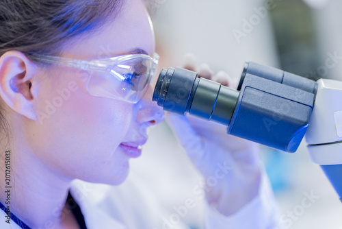 Foto Scientist looks through a microscope in a laboratory during a research session o