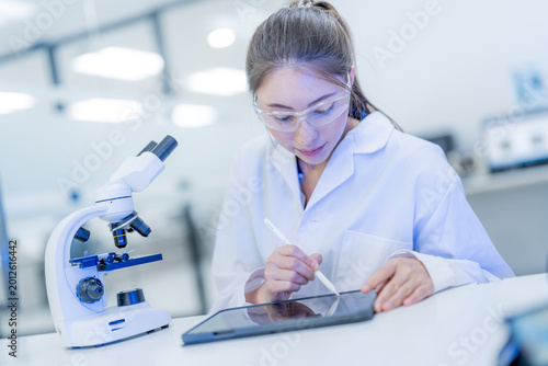 Young scientist works on tablet while analyzing samples in laboratory during daytime hours