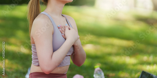 Asian woman practicing mindfulness with hands on chest during outdoor yoga