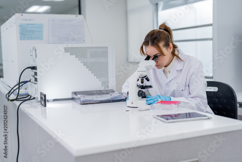 Photography Scientist works with microscope in laboratory setting during daytime in modern f
