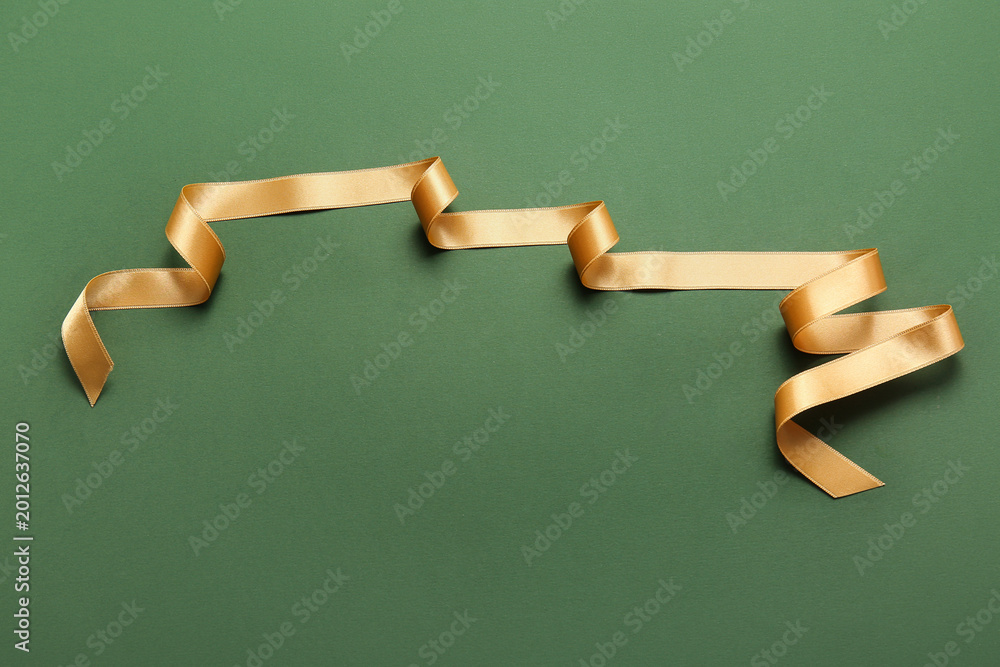 Fototapeta premium Beautiful golden ribbon on green background
