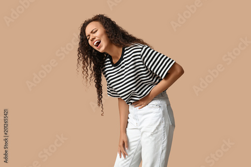 Slika na platnu Young African-American woman with severe stomach ache screaming on beige backgro