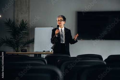 Bild auf Leinwand Business professional in black suit delivers presentation with microphone in mod