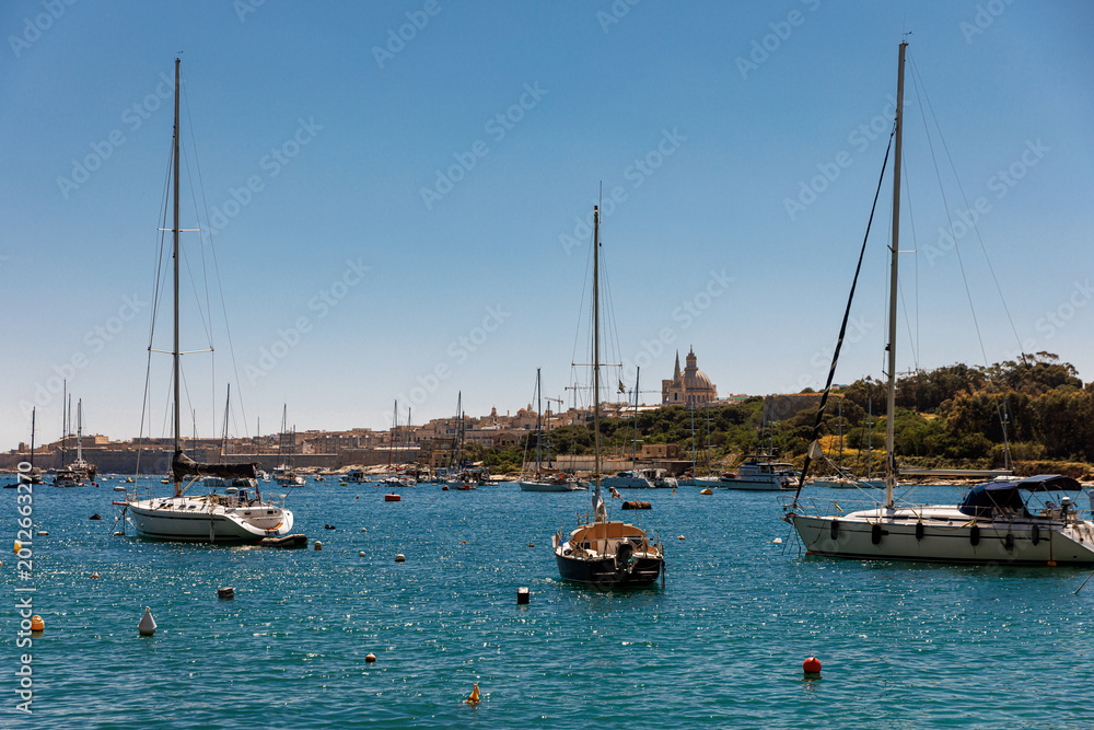 Obraz premium Sailboats anchored in Mediterranean harbor with city view