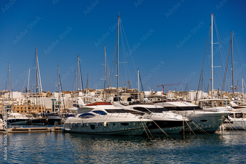 Obraz premium Luxury yachts docked at a pier in a sunny harbor