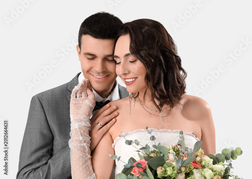 Young wedding couple with bouquet of flowers on white background, closeup