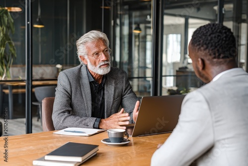 Focused employer listening to a young Black employee during a calm office meeting