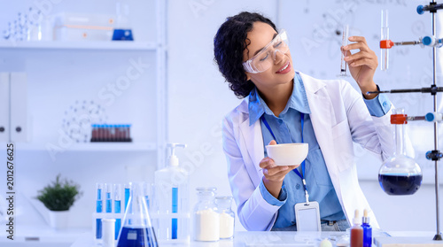 Pretty young African-American female chemist with mortar and test tube workin...