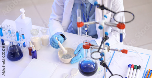 Pretty young African-American female chemist with mortar and pestle working i...