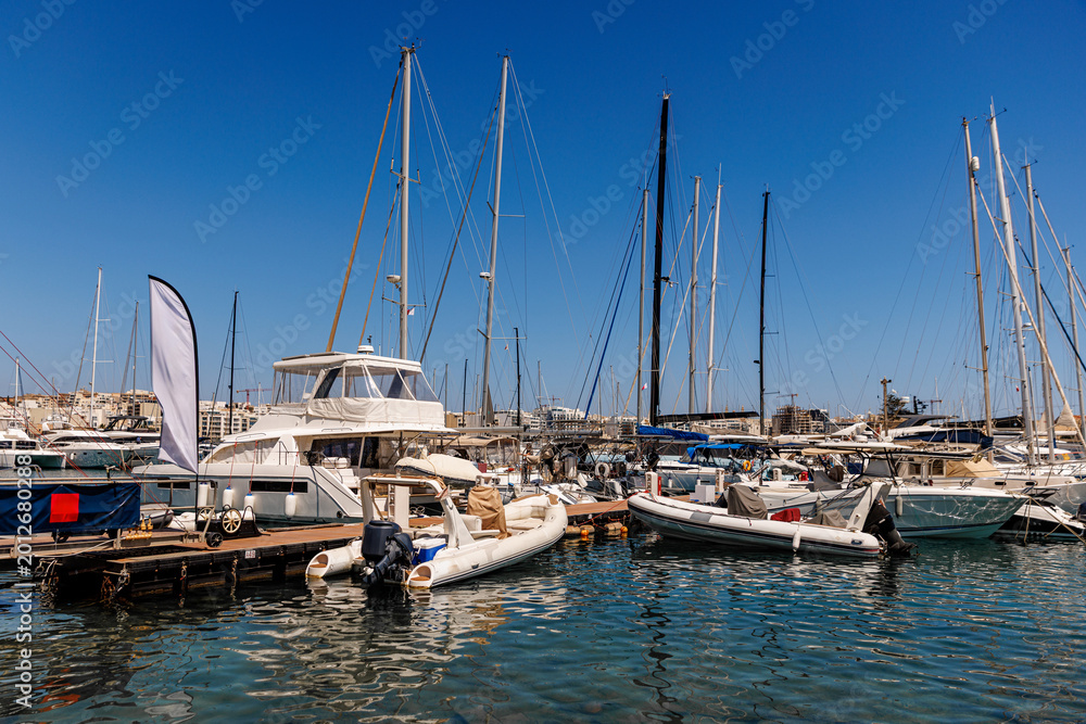 Fototapeta premium Variety of boats and yachts moored at a busy harbor in Malta