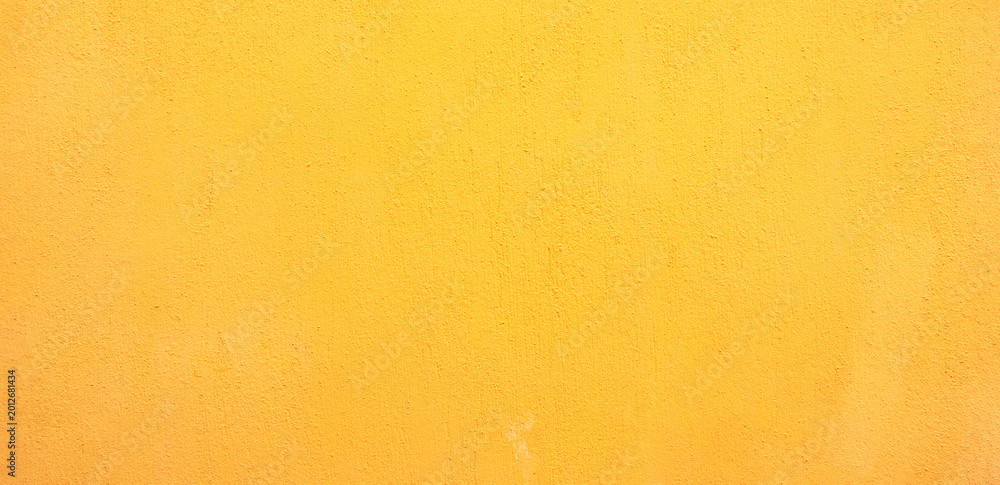 Fototapeta premium Full frame texture of a vibrant mustard yellow painted wall with a subtle grainy plaster finish for a minimalist background.