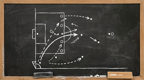 Coach drawing soccer strategy on chalkboard