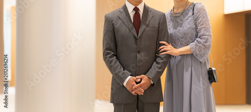 Fotografi ホールの前に立つフォーマルな中高年夫婦