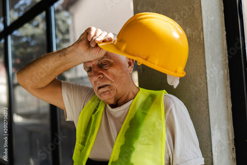 Worker Takes a Break While Holding Yellow Hard Hat at Construction Site During Daytime Hours