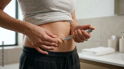 Woman injecting GLP 1 medication into stomach at home, weight loss treatment, wellness routine and healthy lifestyle concept.