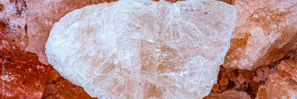 Fototapeta premium Large crystal salt rock placed on a pile of smaller salt rocks in a natural setting during daylight