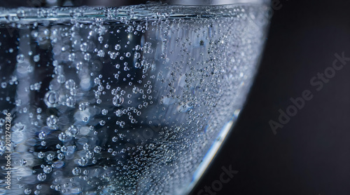 Macro shot of carbonated water bubbles in a glass on dark background