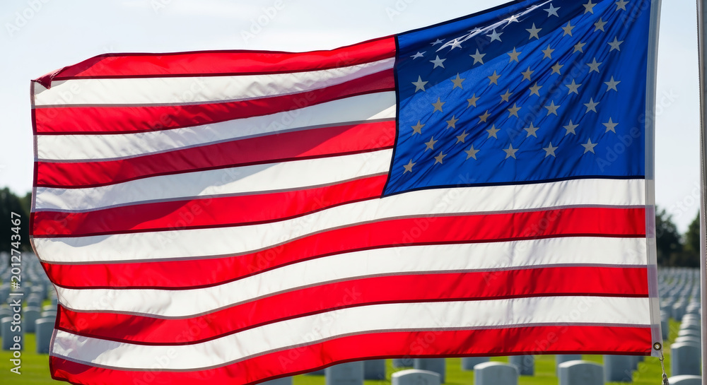 Fototapeta premium American flag waving majestically in a military cemetery on a sunny day with a serene atmosphere