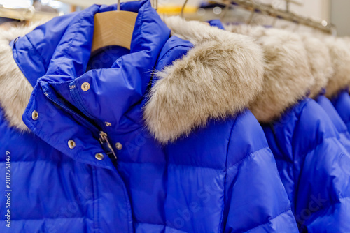 Foto Bright blue winter coat with fur trim displayed in a clothing store at a shoppin