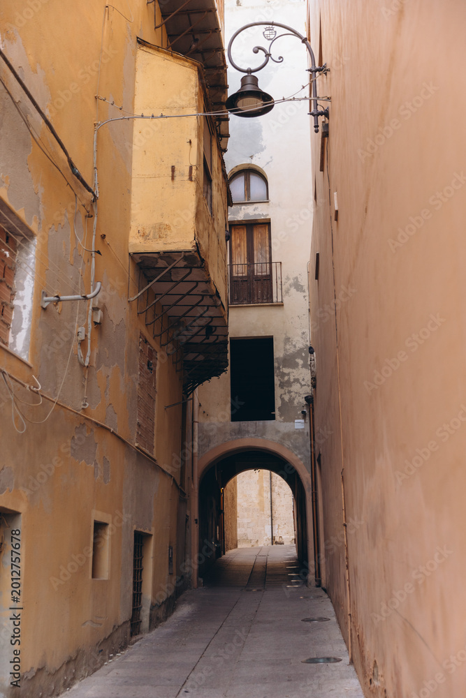 Obraz premium Cagliari old town alleyway, narrow historic street with traditional architecture and arched passage in Sardinia, Italy