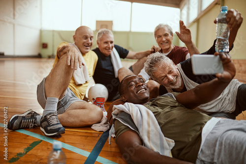 Senior men taking a post-game selfie in gymnasium