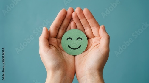 A green happy smiley face held in hands for mental health assessment and child wellness.