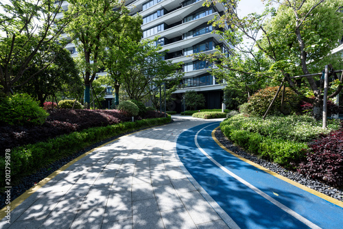 Fotografie Modern residential community with lush greenery surrounding a blue walking path
