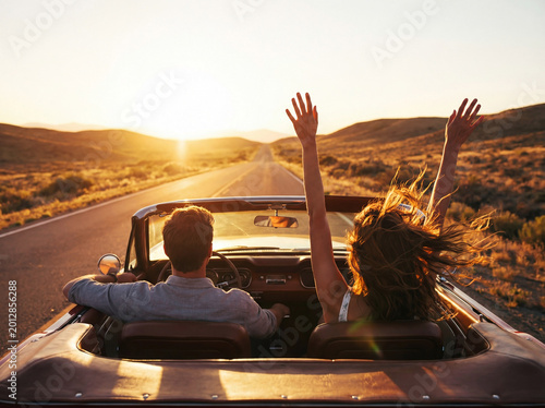 Young couple driving convertible through desert road at sunset, freedom and happiness.