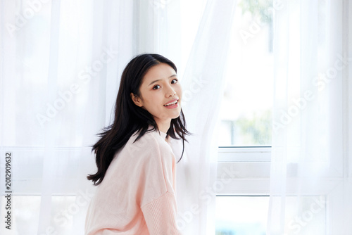 Free Download Smiling young woman by bright window at home - GFXLoad