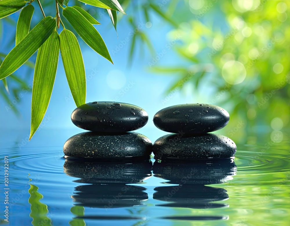 Obraz premium Serene stacked stones in water with green bamboo leaves and blue sky