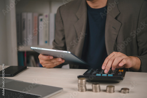 Quadro em tela Man analyzing financial data tablet calculating profit stacks coins desk