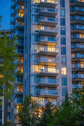 Modern high rise apartment tower with illuminated balconies at twilight
