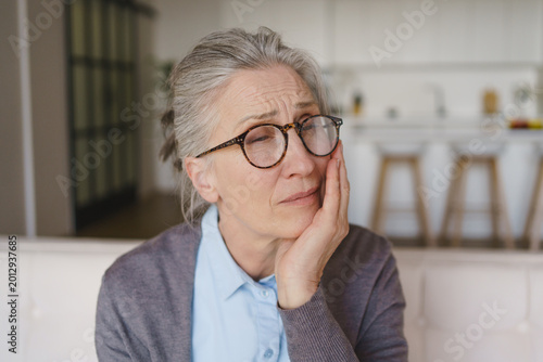 фотографія Elderly woman with tooth pain sitting at home, senior dental health issue, oral