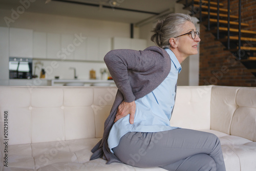 Φωτογραφία Senior woman suffering from back pain at home, elderly health problem, lower bac