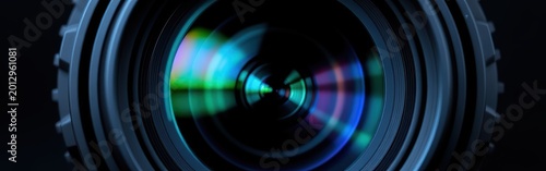 Close-up of a camera lens reflecting colorful lights on a black background