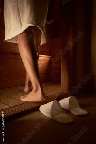 a woman entering a sauna wearing a bathrobe 