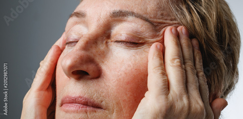 Valokuva Closeup portrait of senior woman touching face in natural skincare and wellness concept