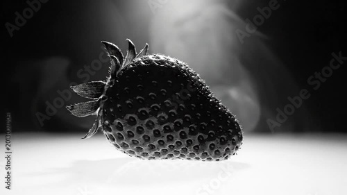 Dramatic black and white close-up shot of a ripe strawberry with focus on texture and light against a dark backdrop