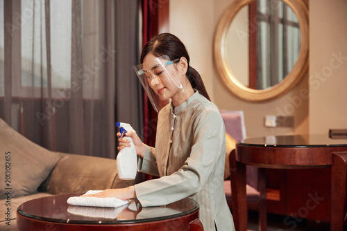 Foto Hotel housekeeper disinfecting table while wearing protective face shield