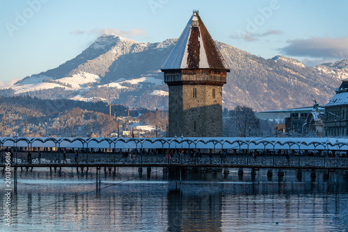 Tableau sur toile The Water Tower framed against the snow-capped peaks of Mount Pilatus in winter,