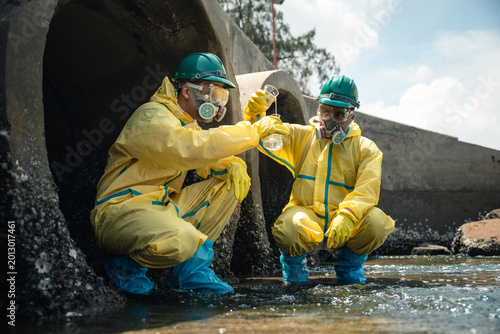 Tablou pe pânză Environmental Worker Collecting Wastewater Samples Near Polluted Industrial Drai
