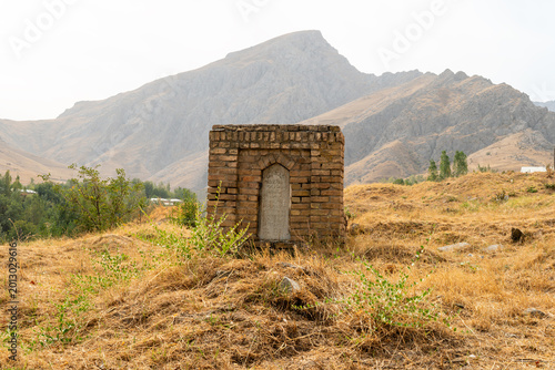 Photos old Muslim grave in the form of a brick stele or tombstone against a mountain background