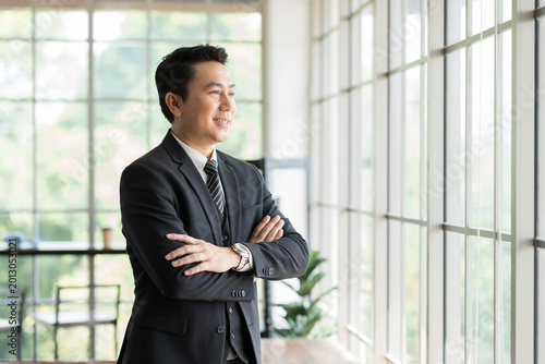 Asian man, businessman wear suit and office. Portrait of Asian business man wear suit at the office. Smiling Asian business man standing with confidence and smile with background modern office