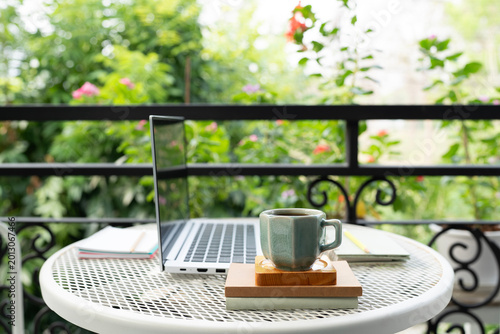 coffee cup and laptop and notebooks , cozy balcony outdoor