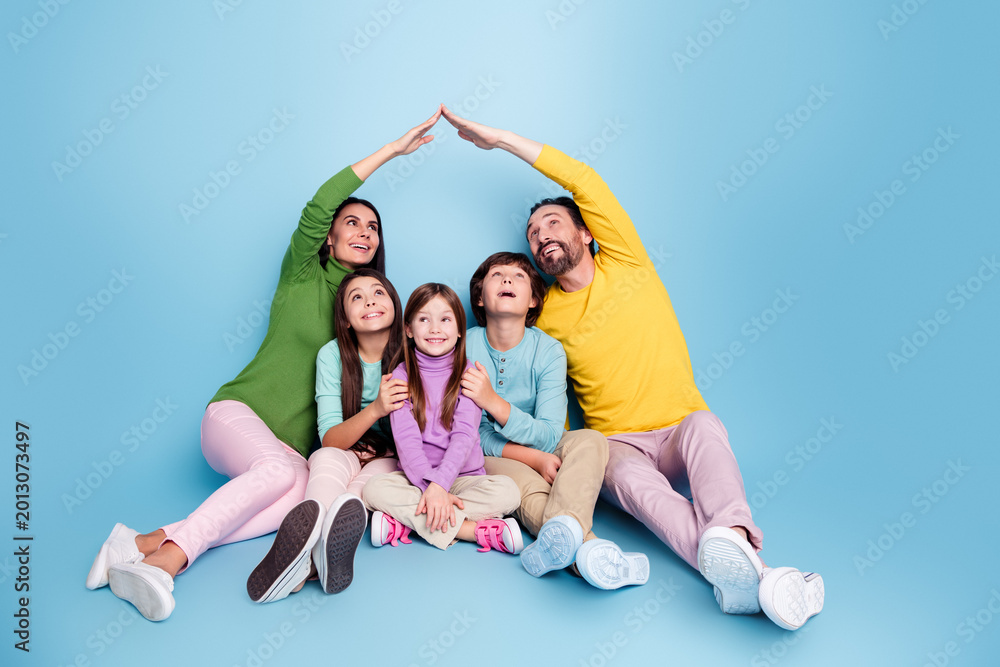 © deagreez - Happy family of five sitting together under parents' roof gesture, smiling children and parents showing love, protection and playful togetherness in a colorful studio portrait © deagreez - Happy family of five sitting together under parents' roof gesture, smiling children and parents showing love, protection and playful togetherness in a colorful studio portrait